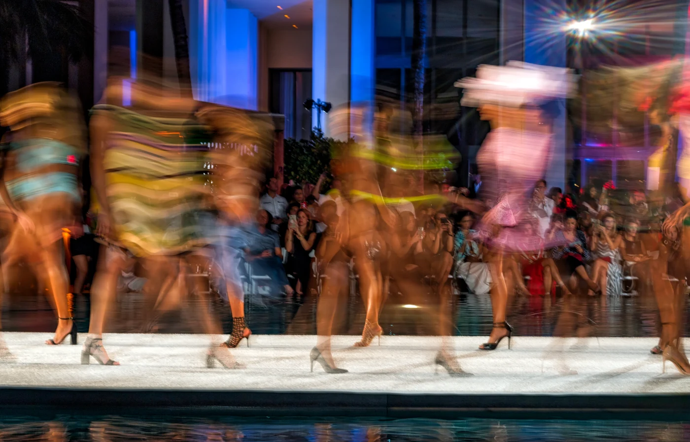 Models in motion on a runway, rendered as streaks of color