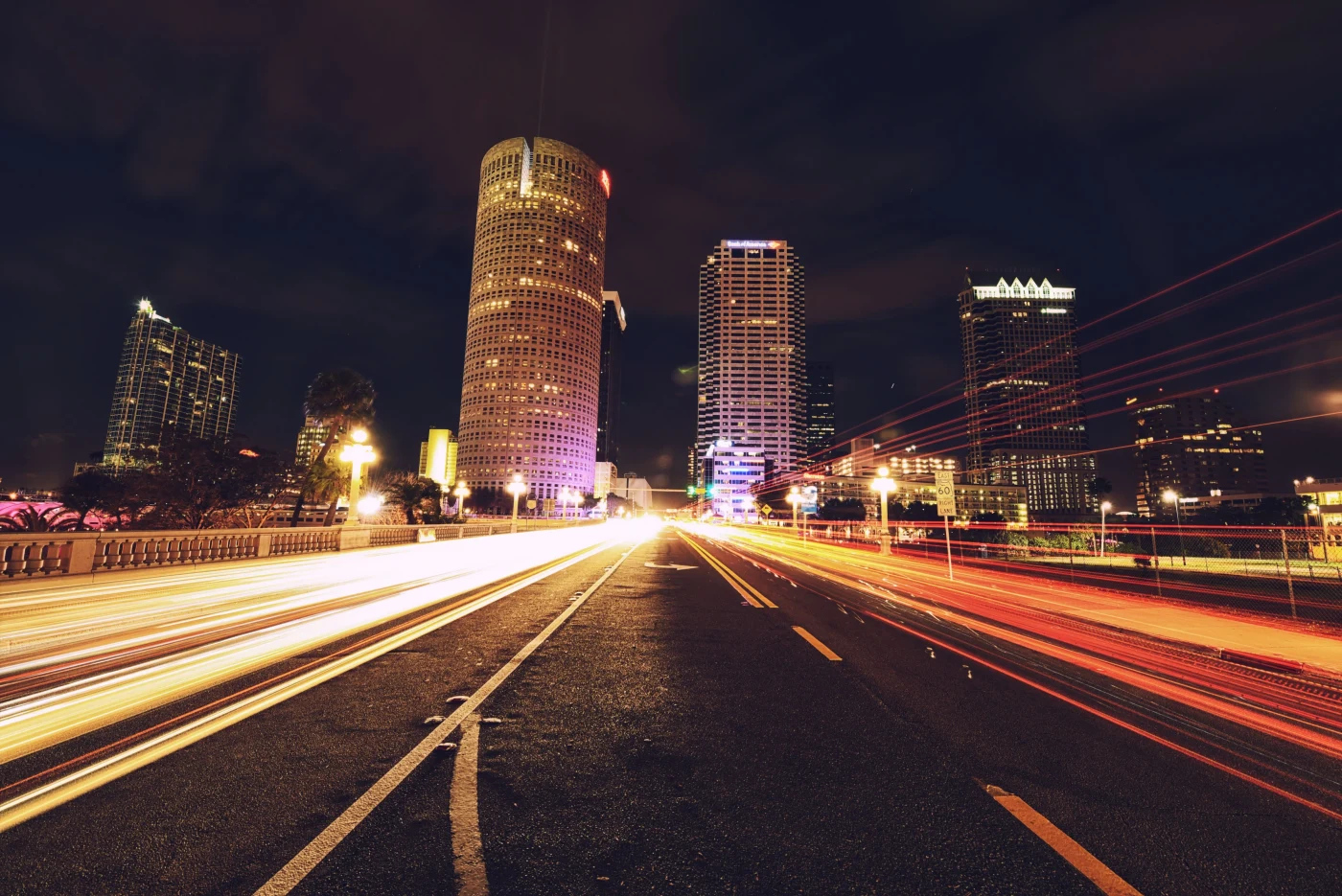 Long-exposure light trails streaming toward downtown Tampa towers at night