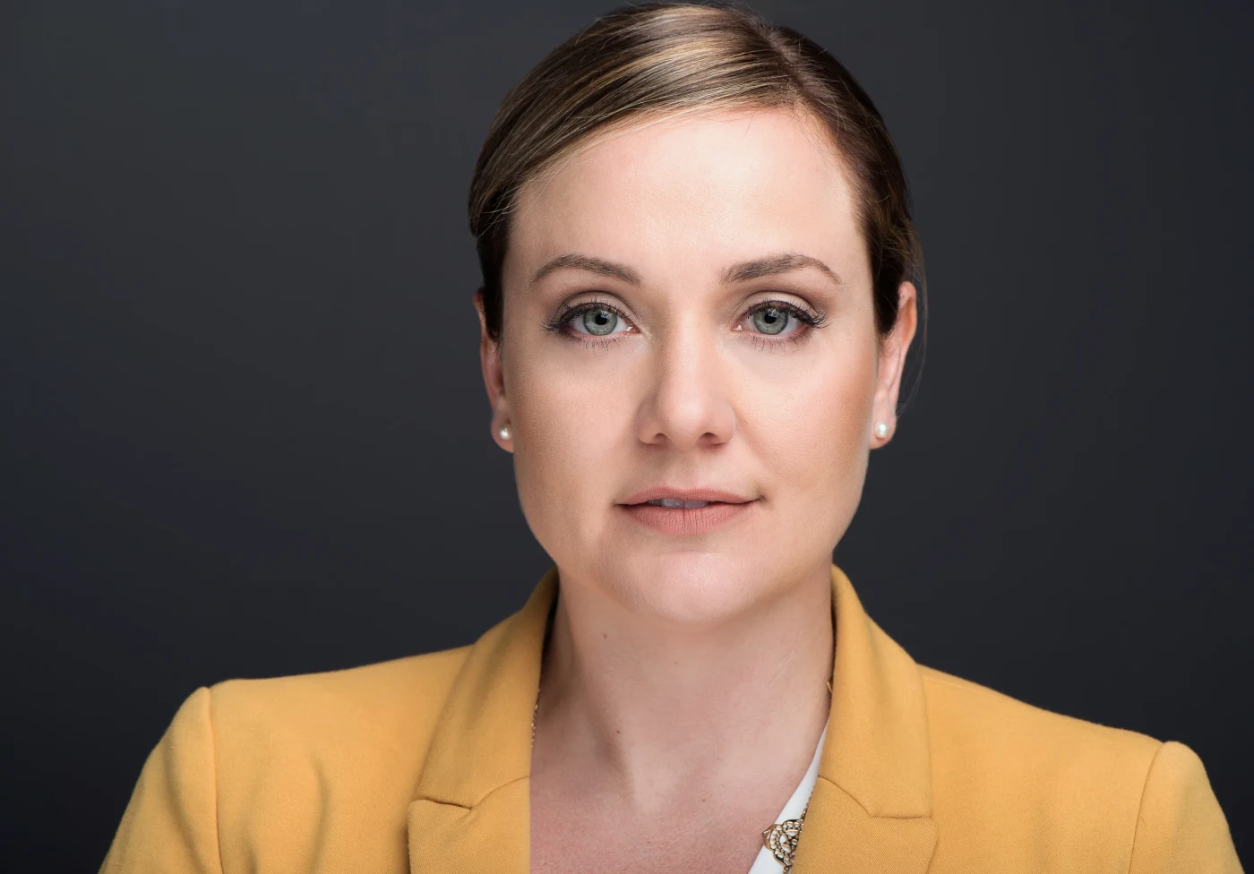 Headshot of a woman in a mustard blazer