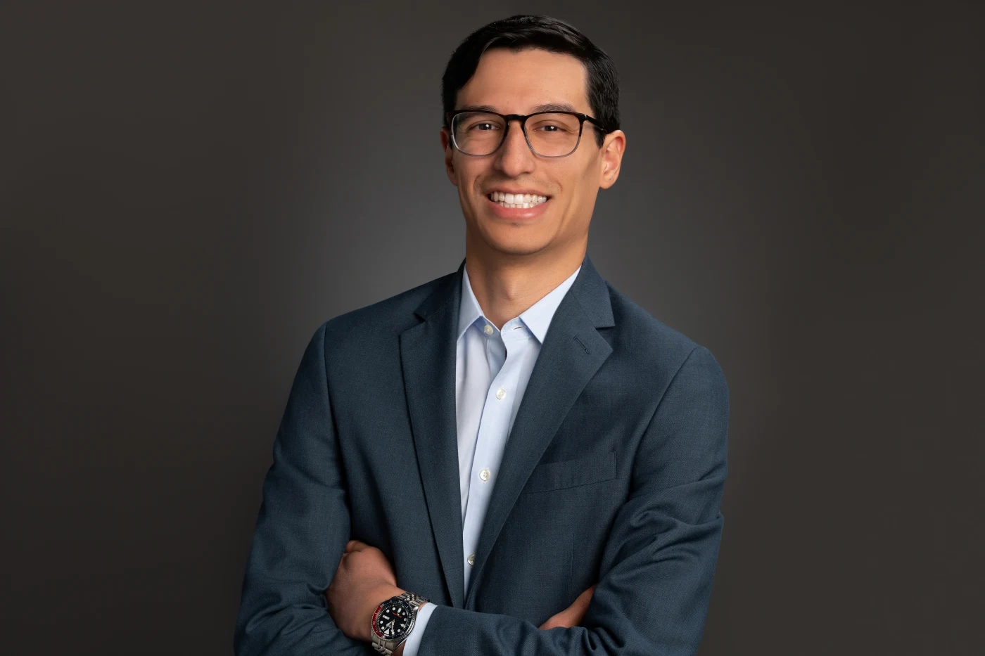 Man in glasses with arms crossed, studio headshot