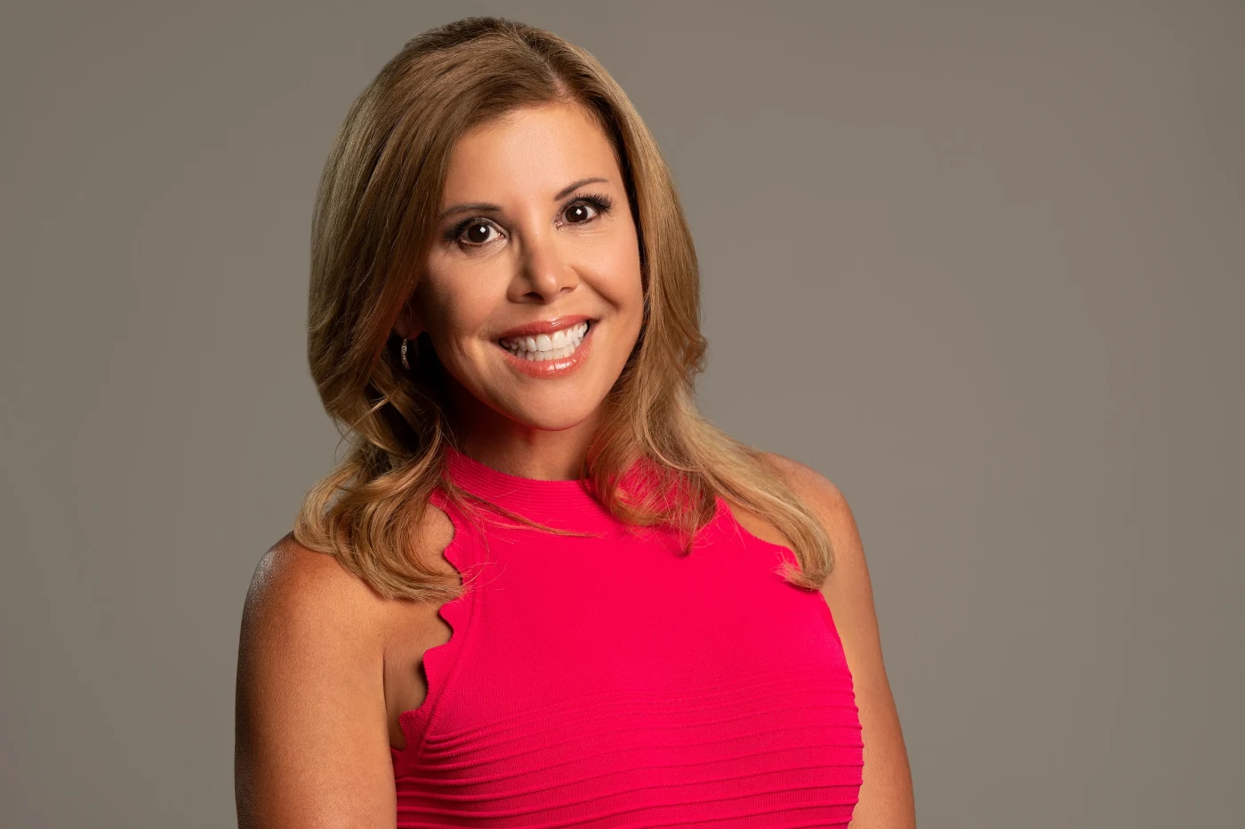 Broadcast-style headshot of a woman in a pink dress