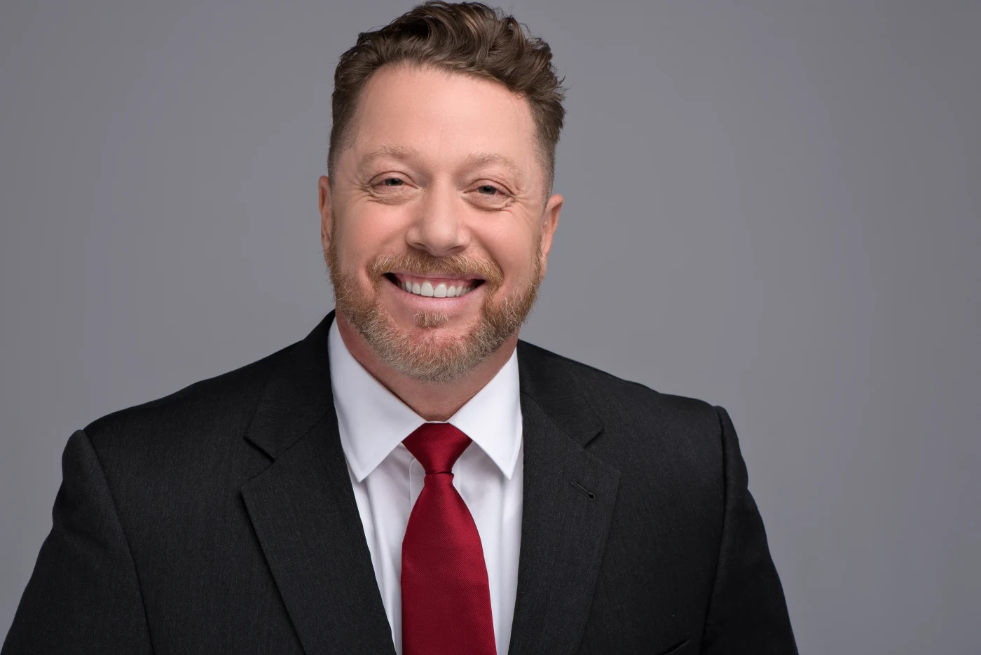 Smiling professional in a black suit and red tie