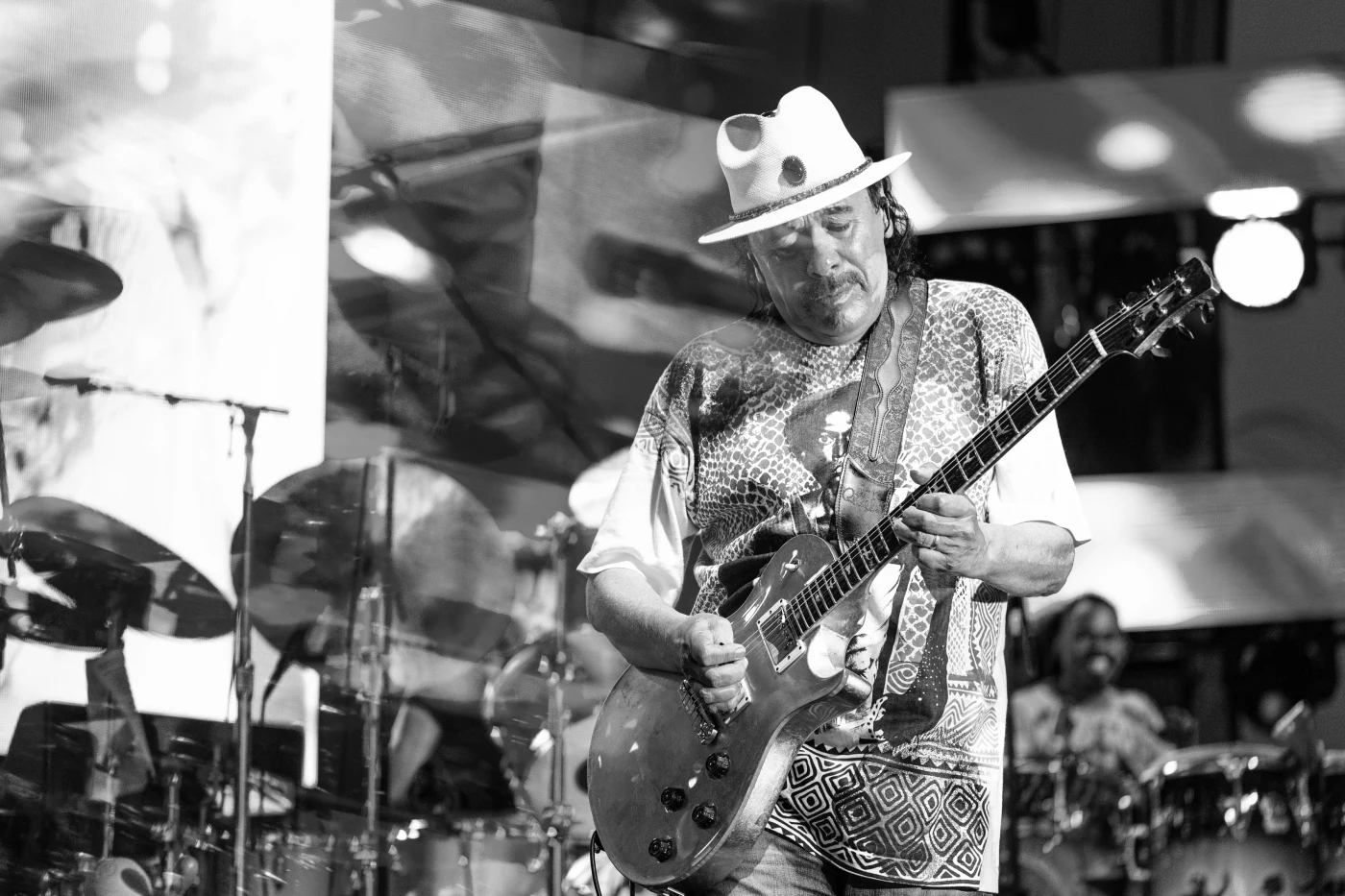 Black and white concert photograph of a guitarist in a white hat