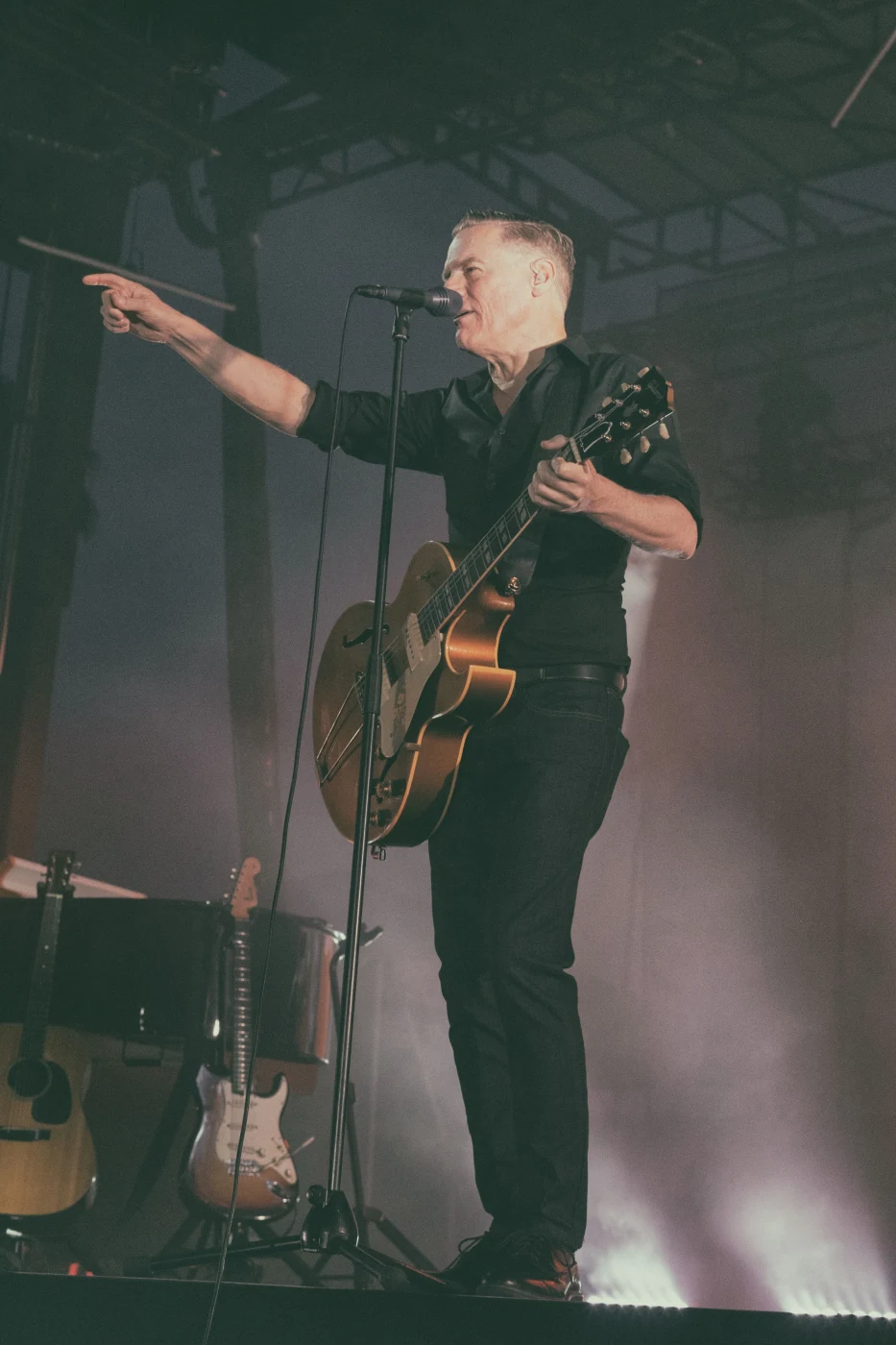 Singer with acoustic guitar pointing out to the crowd