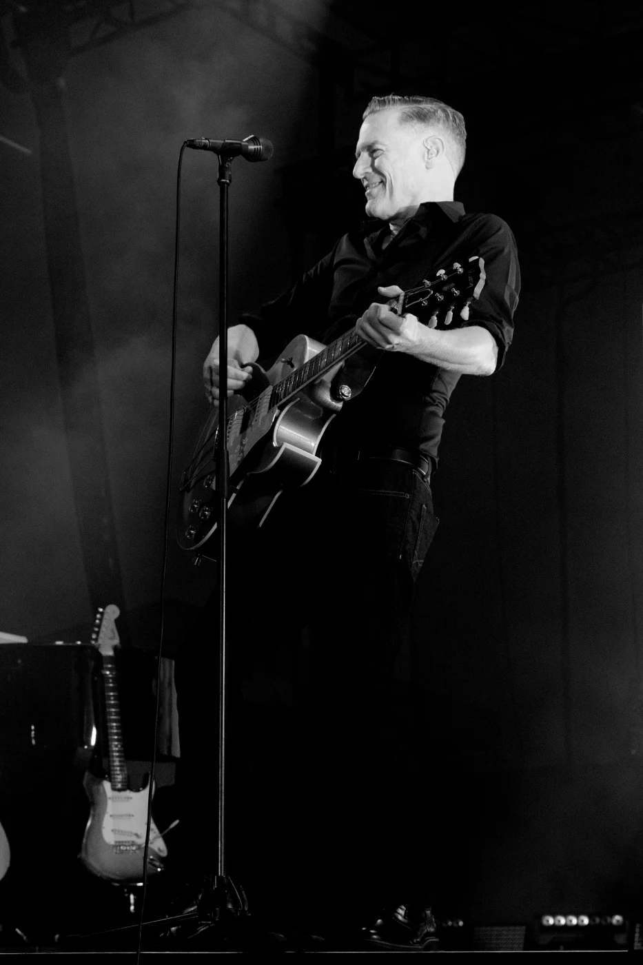 Black and white photograph of a singer with guitar in a single spotlight