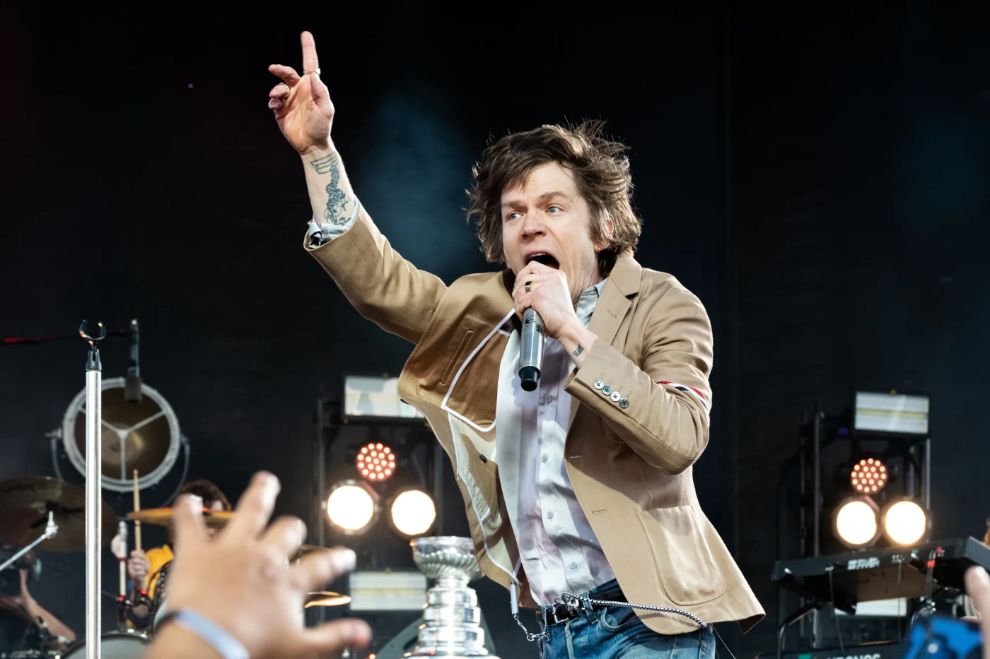 Frontman pointing skyward as the crowd reaches up