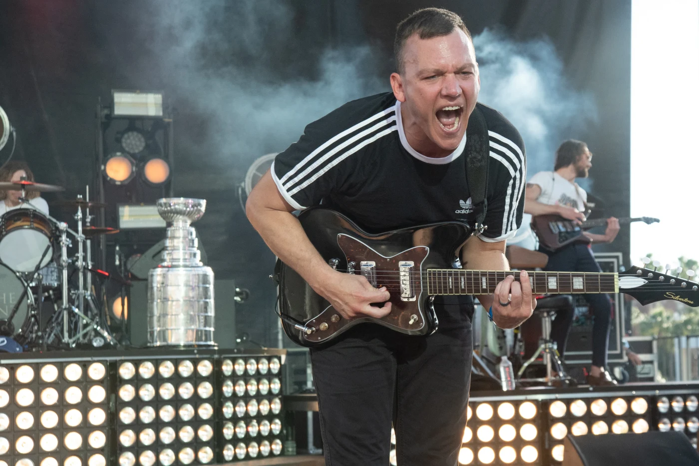 Guitarist roaring on stage beside the light banks