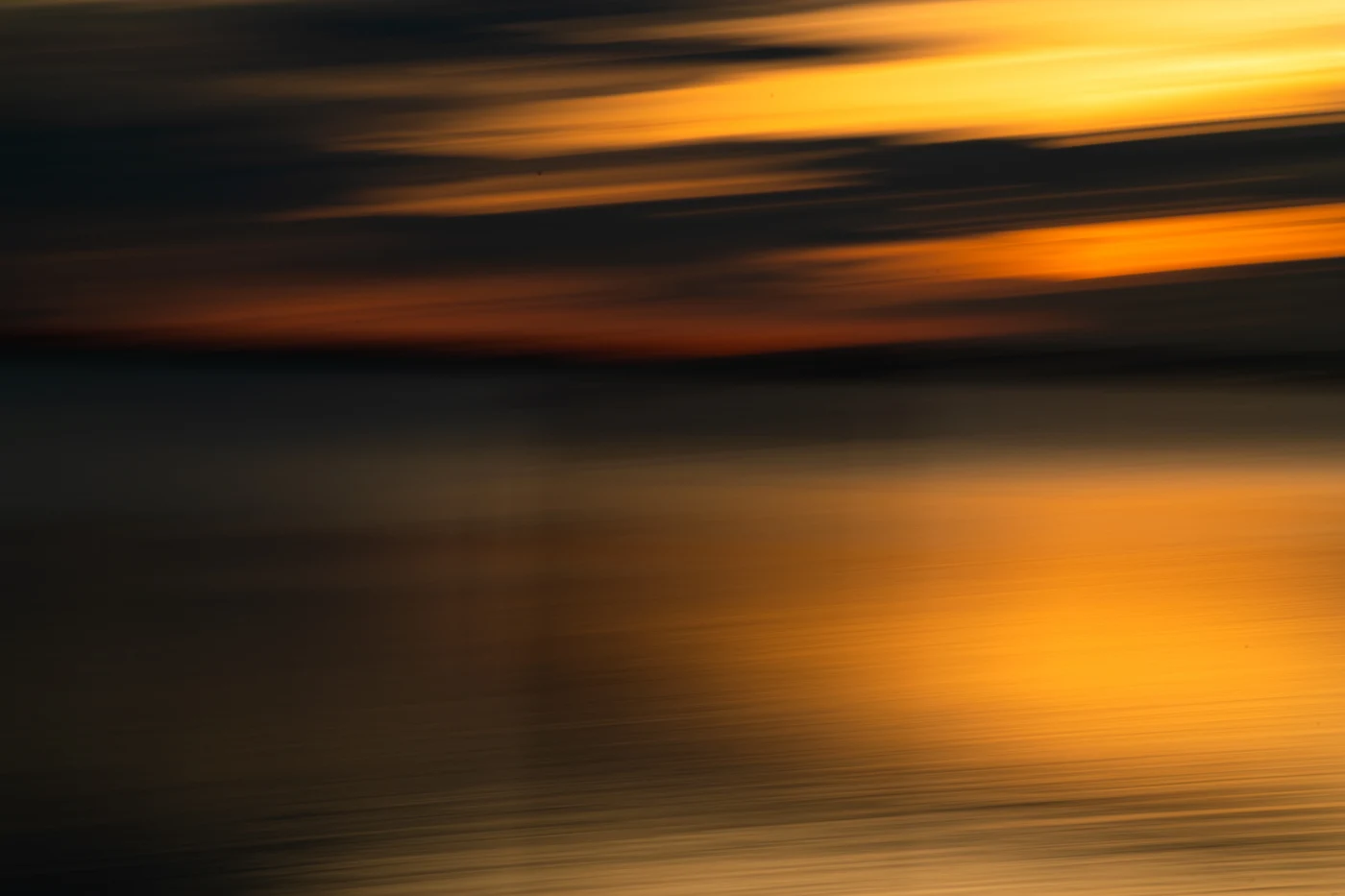 Abstract shutter-drag sunset in molten orange and gold