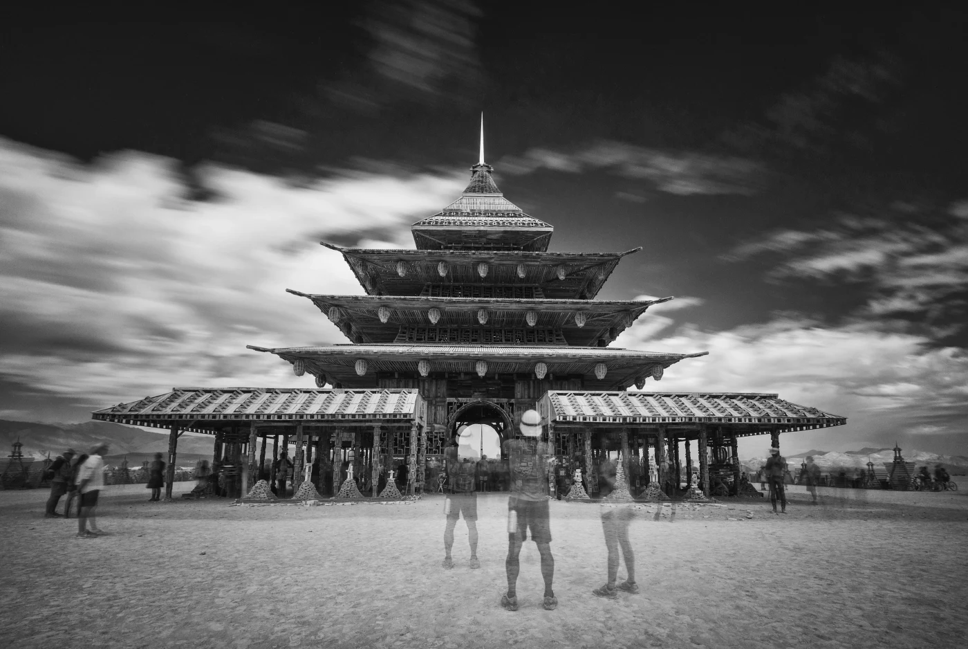 Black and white photograph of a tiered wooden temple under dramatic skies